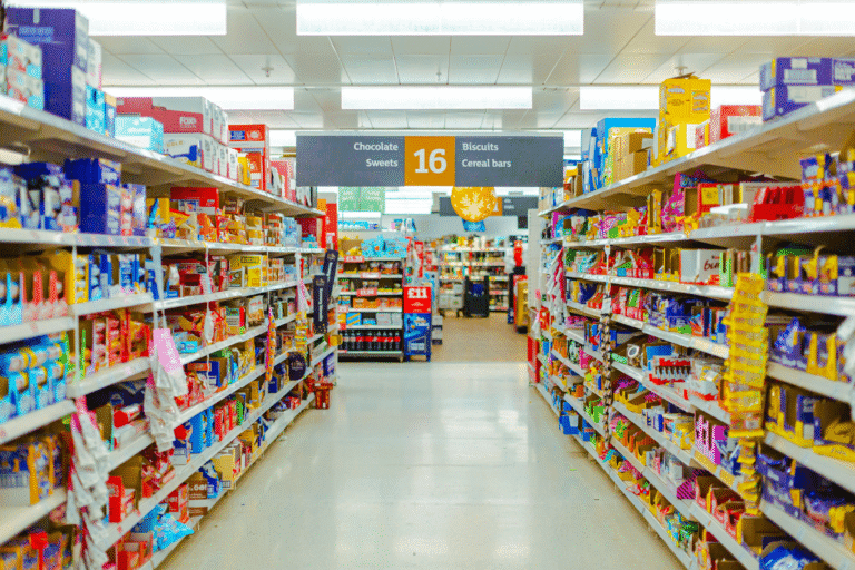 Kadr wykonany w supermarkecie w Londynie. Pokazuje obfitość oferty, ekspozycję żywności i handlowy wymiar systemu żywnościowego.